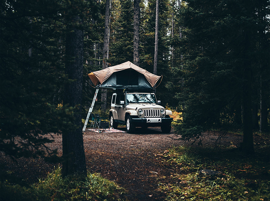 4x4 équipé d'une tente de toit au cœur d'une forêt prêt pour une nuit en pleine nature