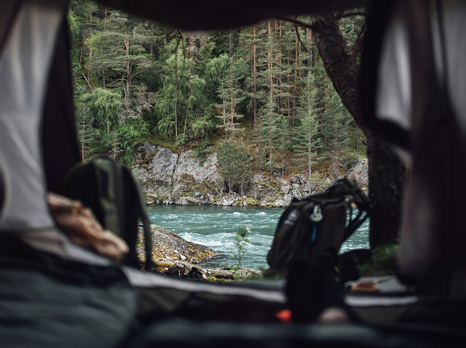 Vue sur une rivière de montagne depuis l'interieur d'une tente 