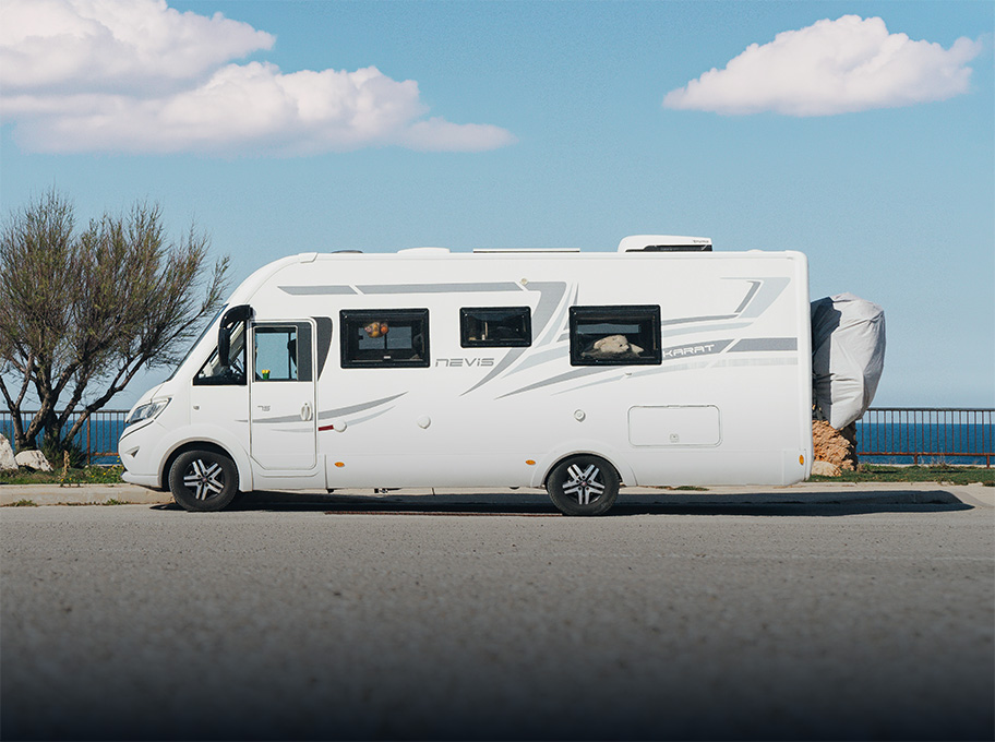 Camping-car aménagé en pleine nature avec chaises et équipements installés devant la porte latérale