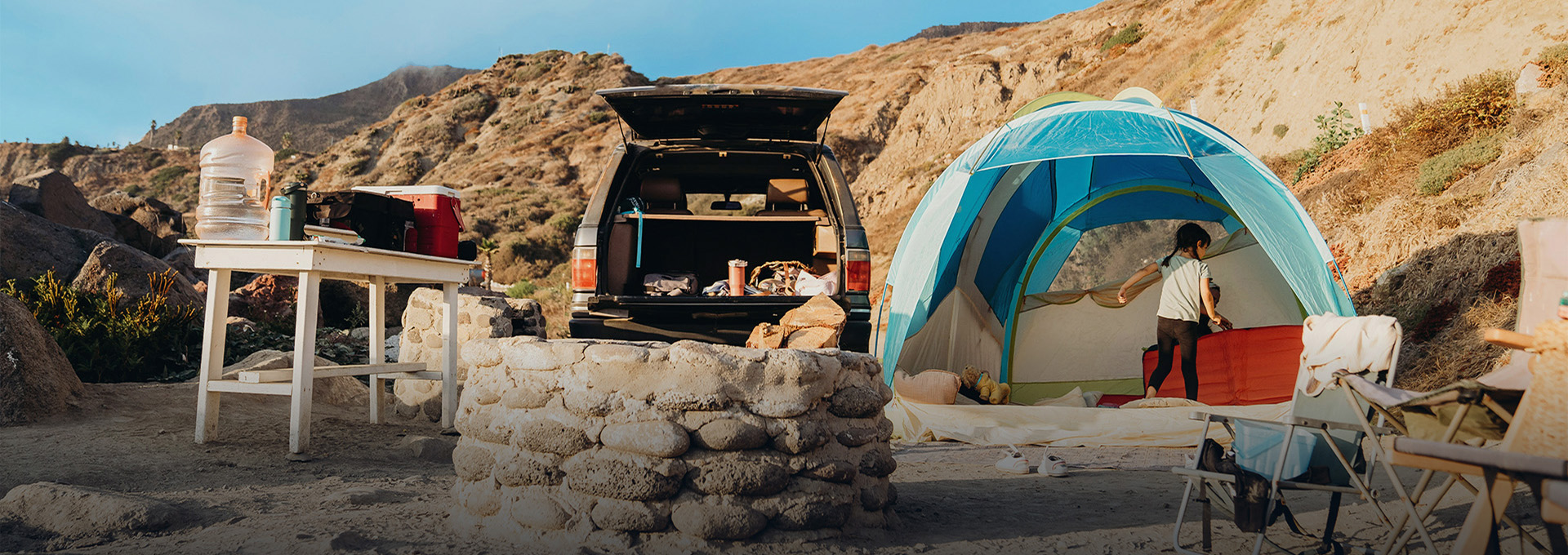 Setup camping extérieur avec tente, coffre de voiture ouvert et table de camp en franc de falaise